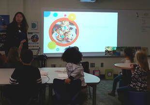 Photo of Roxanne teaching young, engaged students during an author visit. 
